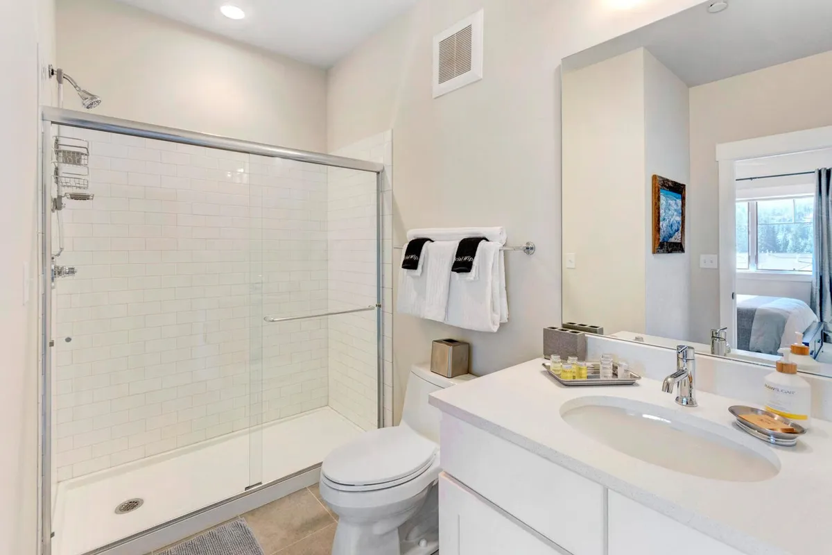 A modern bathroom featuring a spacious shower area, vanity with sink, and a large mirror. The space is designed for relaxation and rejuvenation, with clean lines and thoughtful touches that evoke a sense of luxury suitable for both master and guest bathrooms.
