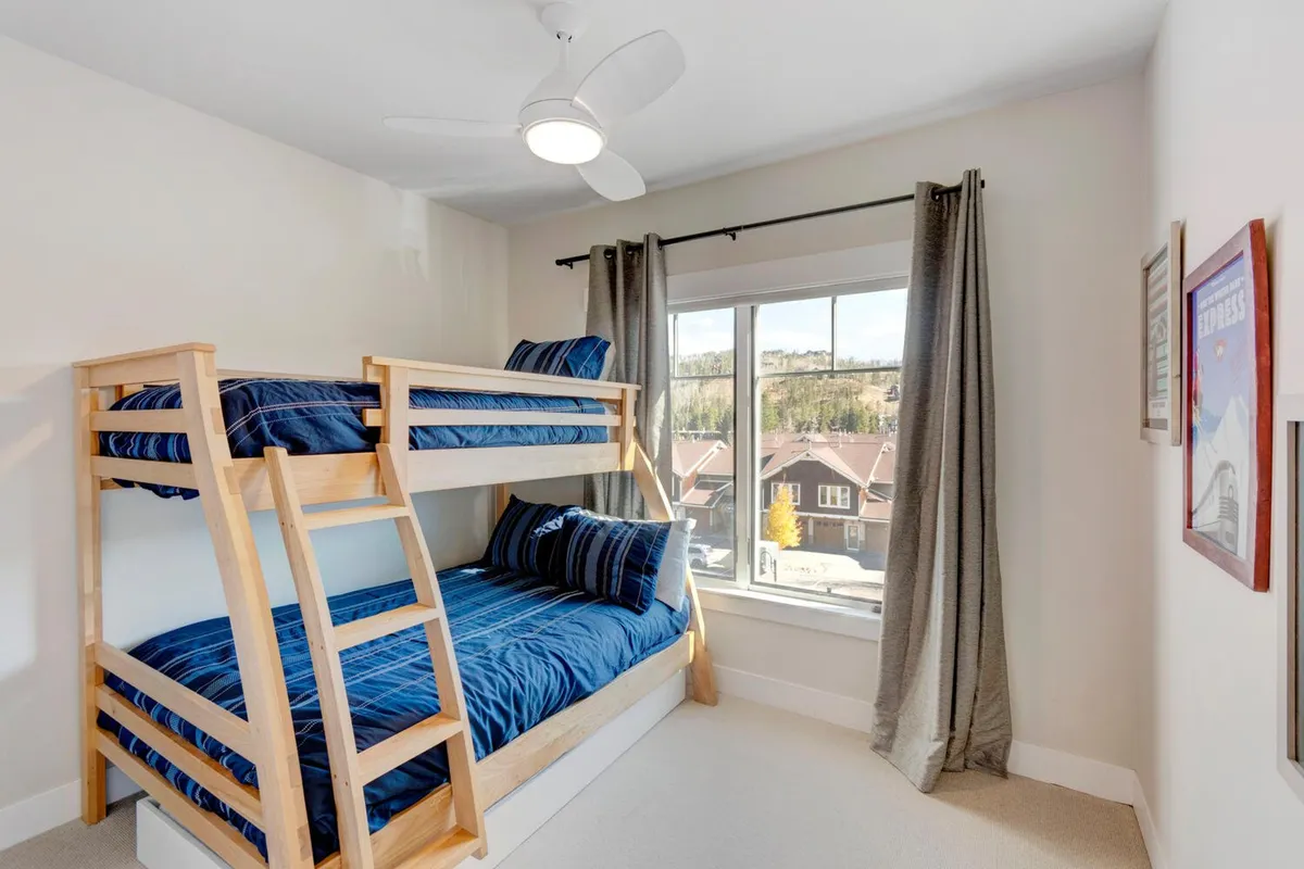 A cozy bunk bed nook with playful striped bedding, a window with natural light, and a relaxed, cheerful vibe. The arrangement is perfect for sleepovers and offers flexible sleeping options for groups.