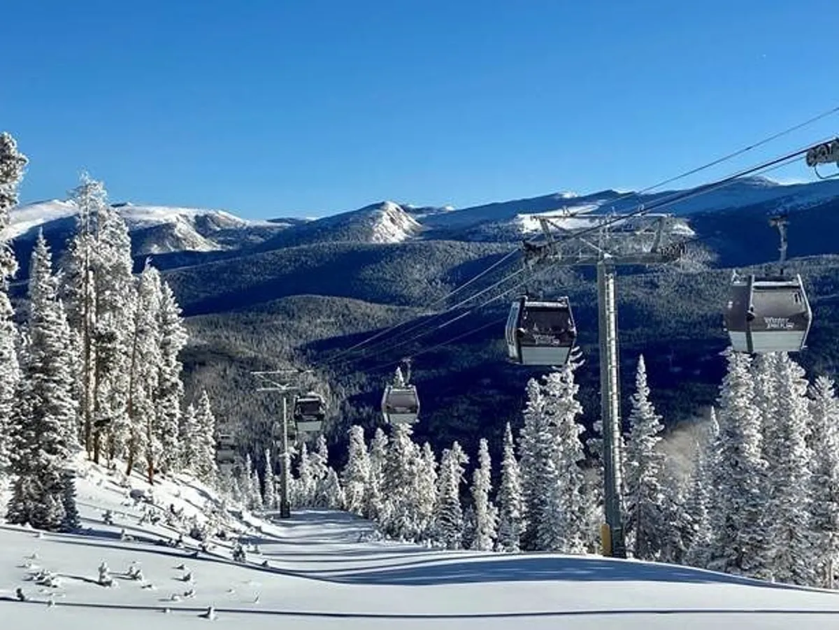 A striking exterior view of snow-covered mountains framed by pine trees, with gondola lifts ascending the slopes. The foreground highlights the pristine ski and snowboard terrain, inviting viewers to imagine themselves on an alpine adventure.