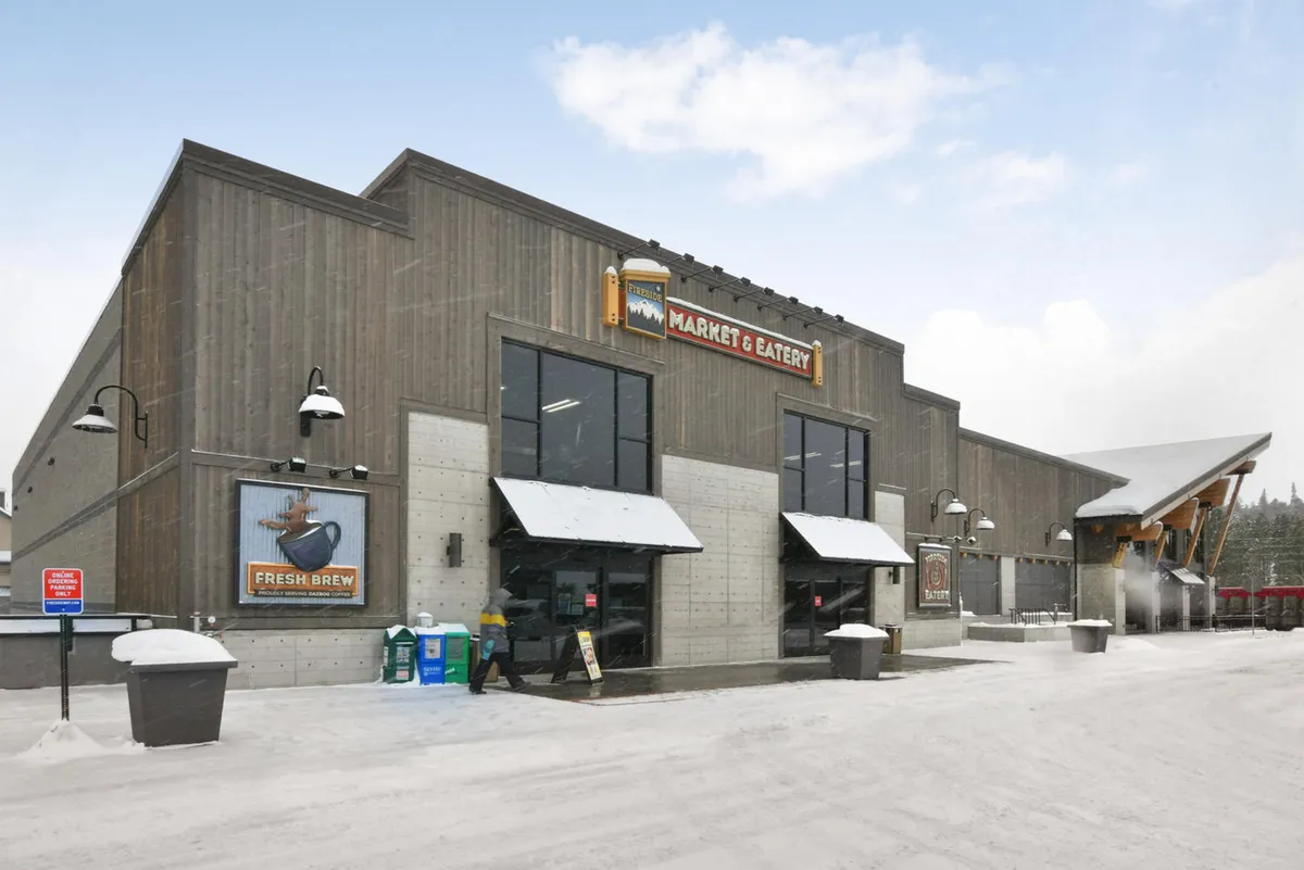 An exterior shot shows the entrance to a local market and eatery, with signage promoting fresh brews and local produce. The doors are open and welcoming, inviting residents to easily stock up on groceries or grab a coffee just steps from home.
