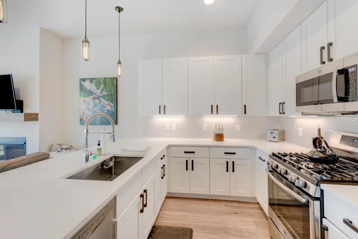 This image features a warm and welcoming open-concept kitchen, centered around a spacious island with seating. Stainless steel appliances gleam under natural light, while tasteful artwork adorns the wall, creating an inviting setting for both cooking and socializing. The scene hints at lively family gatherings and culinary adventures, perfectly matching the 'chef’s kitchen' feature.
